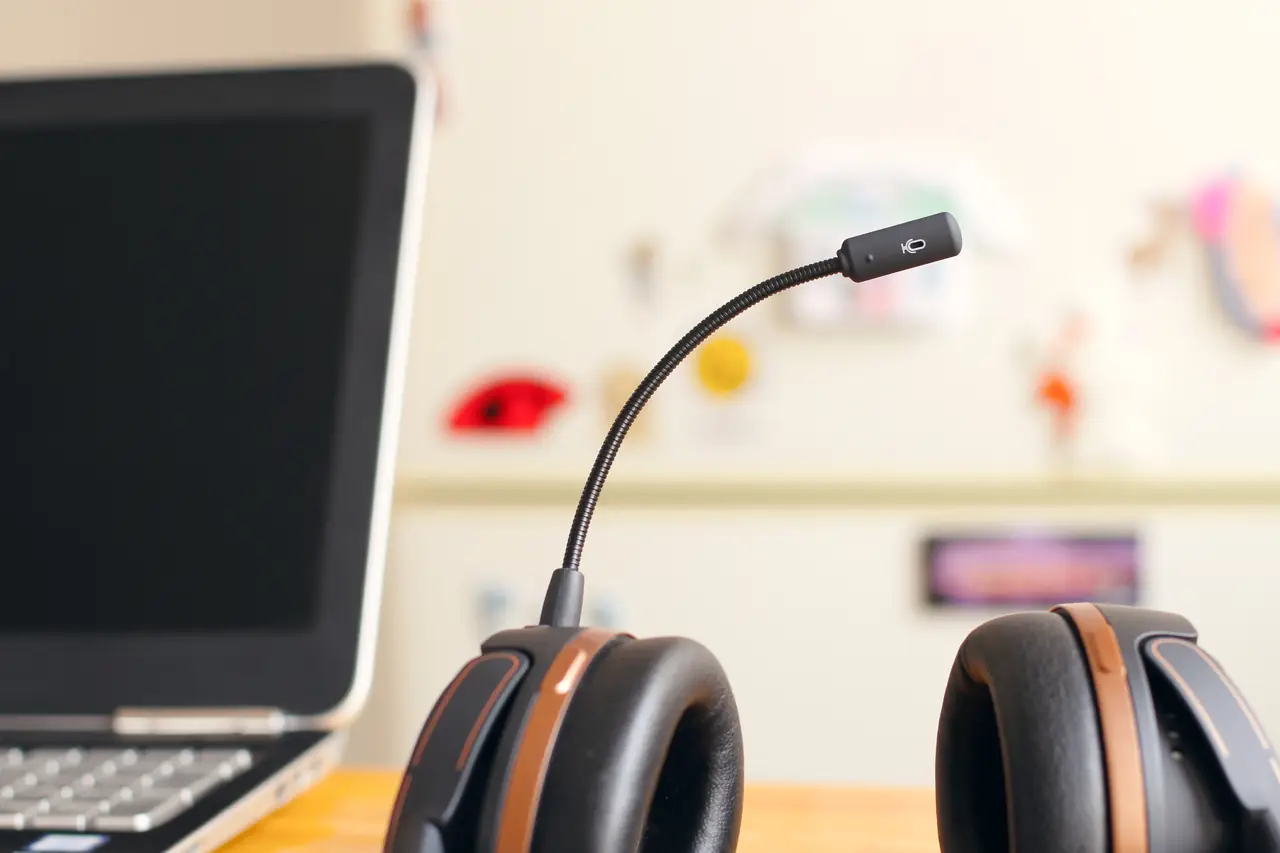 Cuffie con microfono su una scrivania accanto a un computer portatile