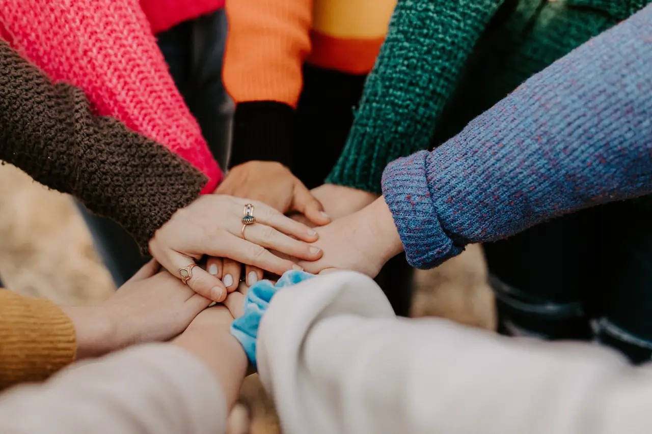 Mani di persone diverse sovrapposte in segno di collaborazione